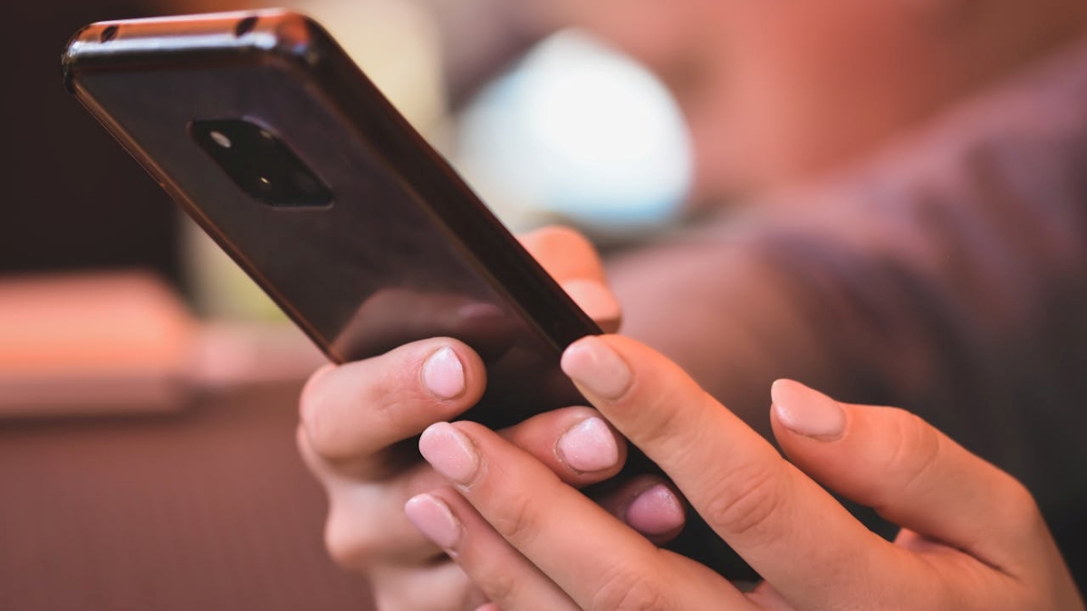 Pessoa mexendo no celular preto